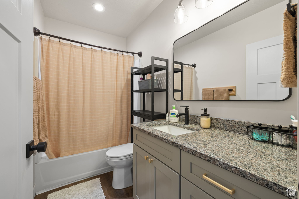 Bathroom featuring vanity, toilet, shower / bathtub combination with curtain, recessed lighting, and wood finished floors