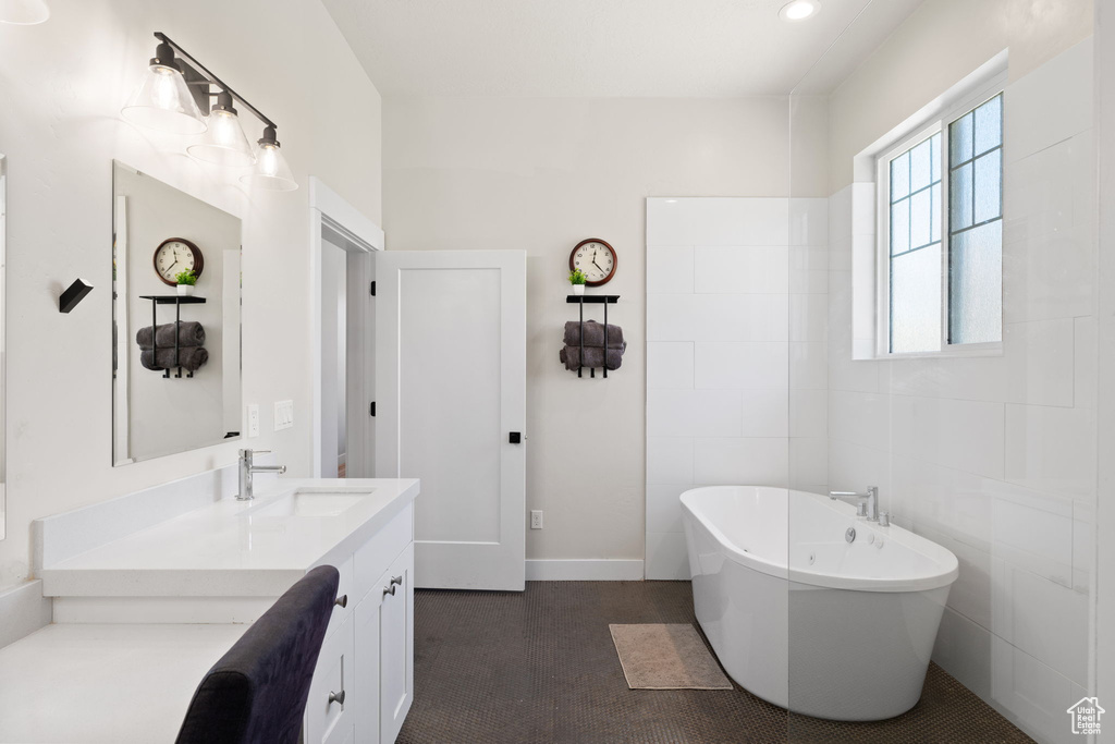 Bathroom with vanity, baseboards, and a soaking tub