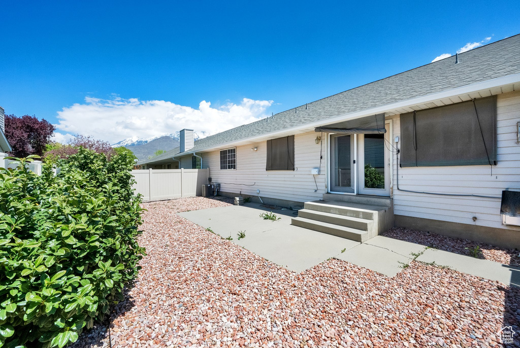 View of front of property featuring fence, roof with shingles, a patio, and entry steps