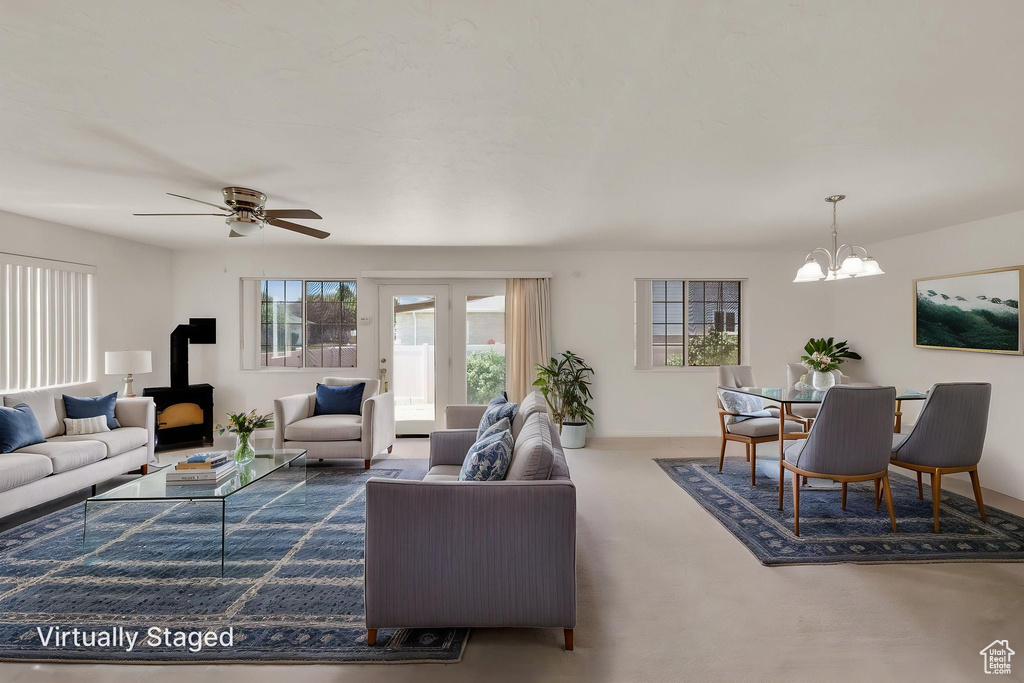 Carpeted living area featuring a wood stove, a chandelier, and a ceiling fan