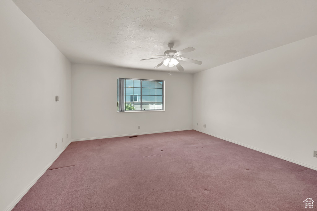 Empty room featuring light colored carpet, a ceiling fan, and baseboards