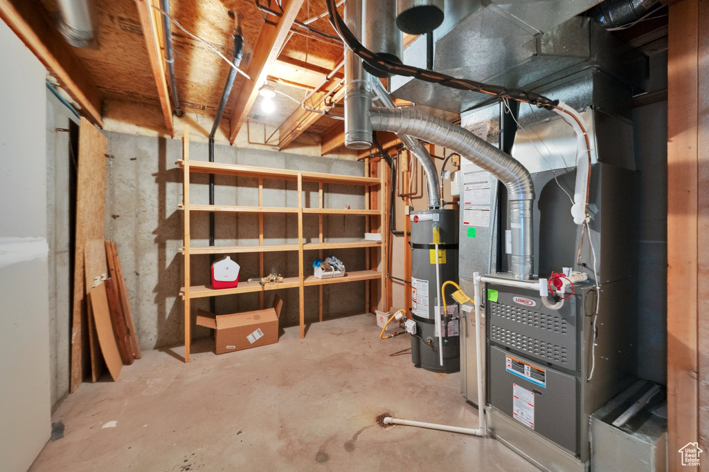 Unfinished below grade area featuring strapped water heater and heating unit