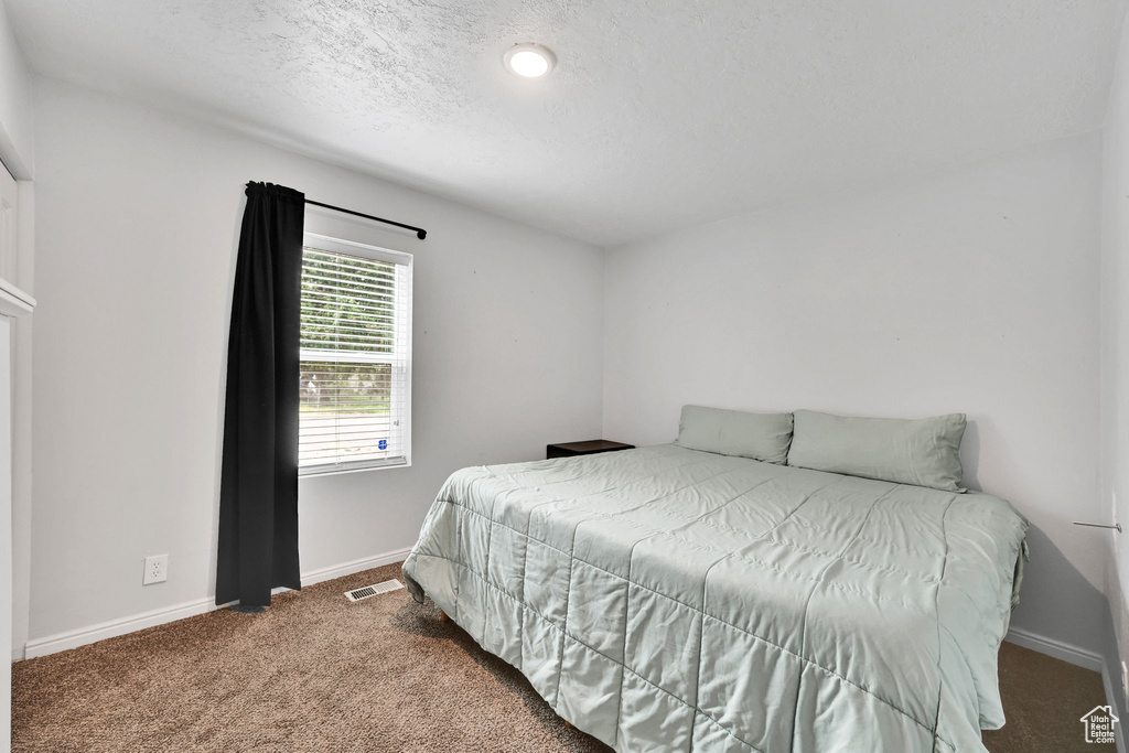 Carpeted bedroom with baseboards and a textured ceiling