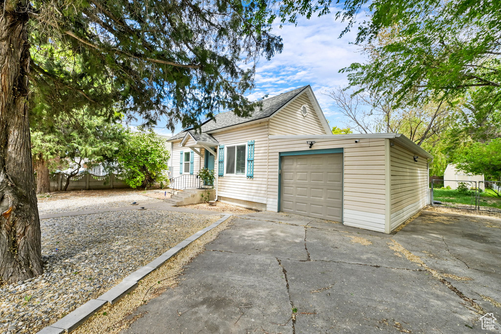 View of front of home featuring driveway, fence, an attached garage, and roof with shingles
