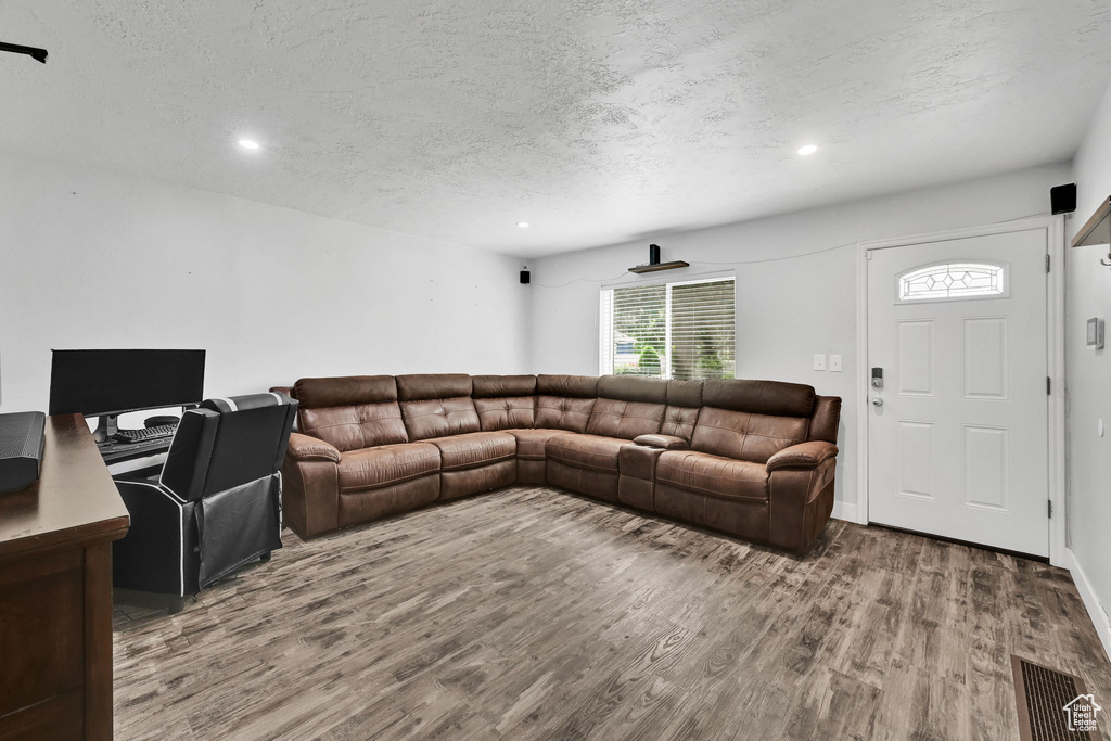 Living room featuring wood finished floors, a textured ceiling, and recessed lighting