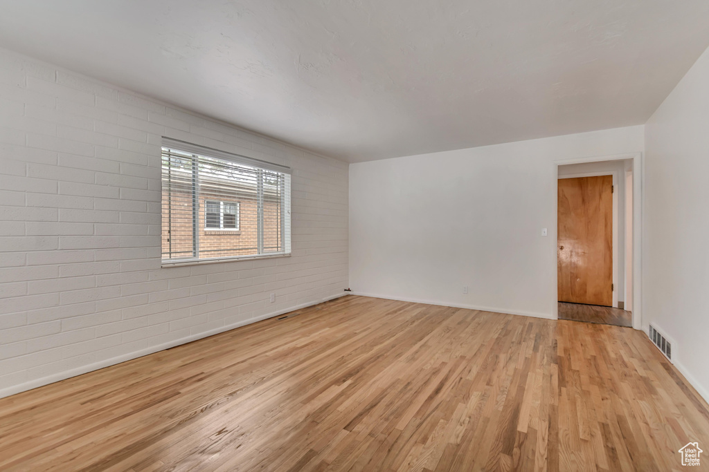 Spare room with light wood finished floors, baseboards, and brick wall