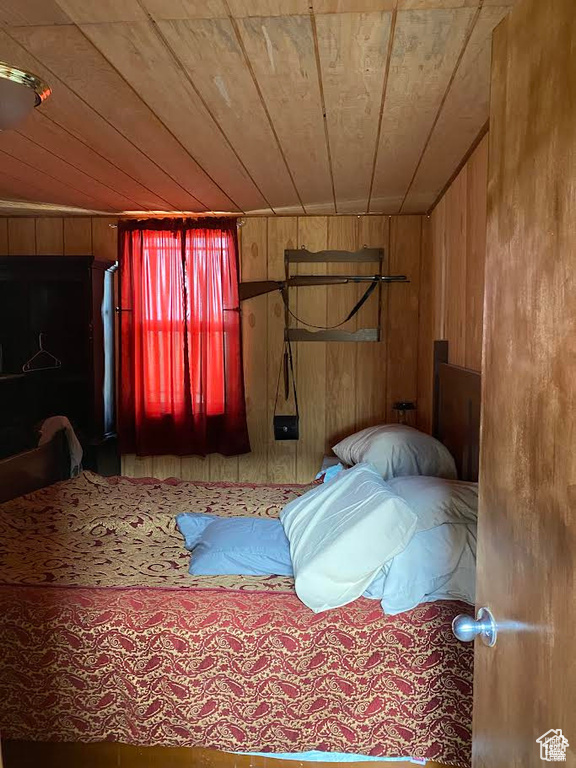 Bedroom featuring wooden ceiling and wooden walls