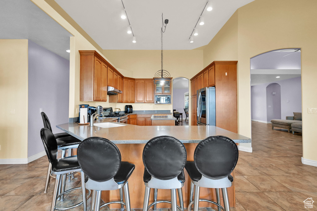 Kitchen with a sink, a peninsula, stainless steel appliances, under cabinet range hood, and arched walkways