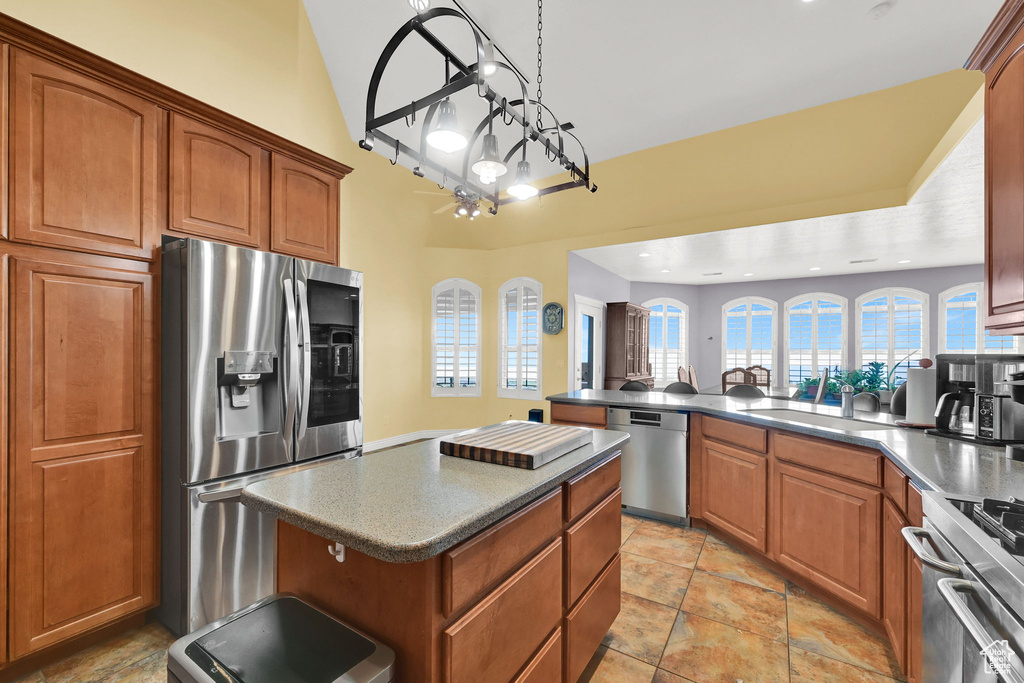 Kitchen featuring a sink, a peninsula, brown cabinets, and appliances with stainless steel finishes