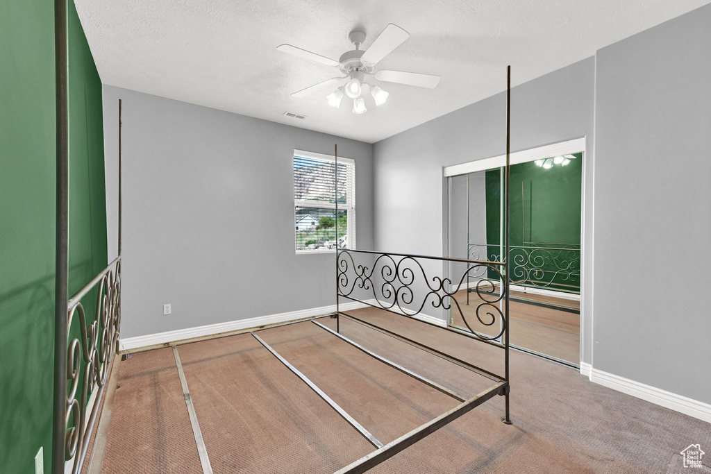 Carpeted bedroom featuring visible vents, baseboards, and ceiling fan