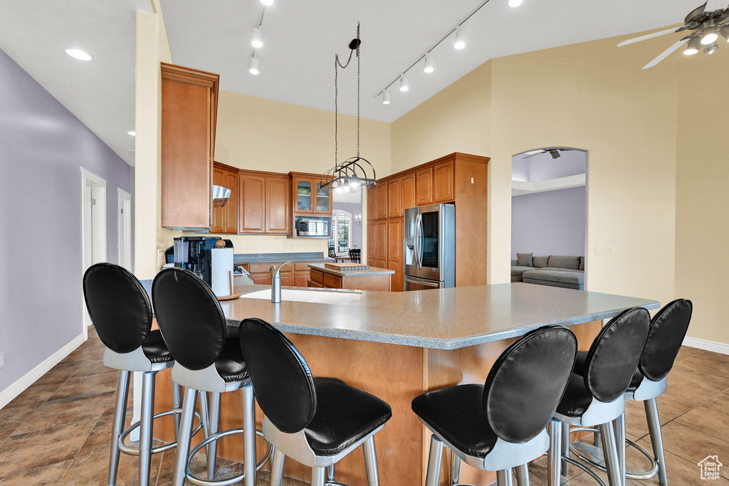 Kitchen featuring a breakfast bar, a center island, a ceiling fan, baseboards, and appliances with stainless steel finishes