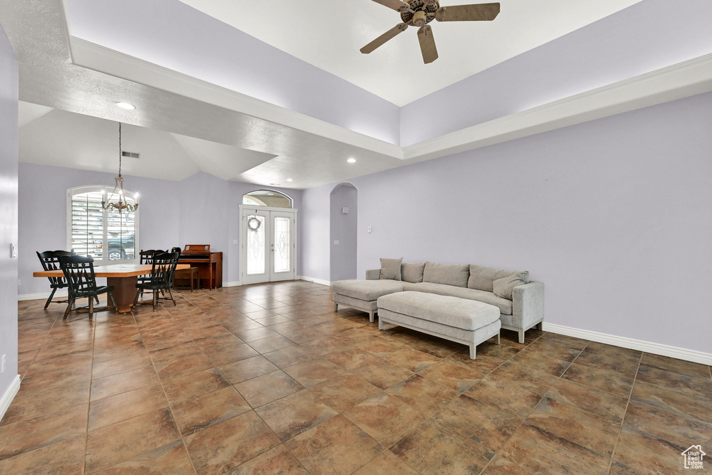 Living room with baseboards, ceiling fan with notable chandelier, arched walkways, and recessed lighting