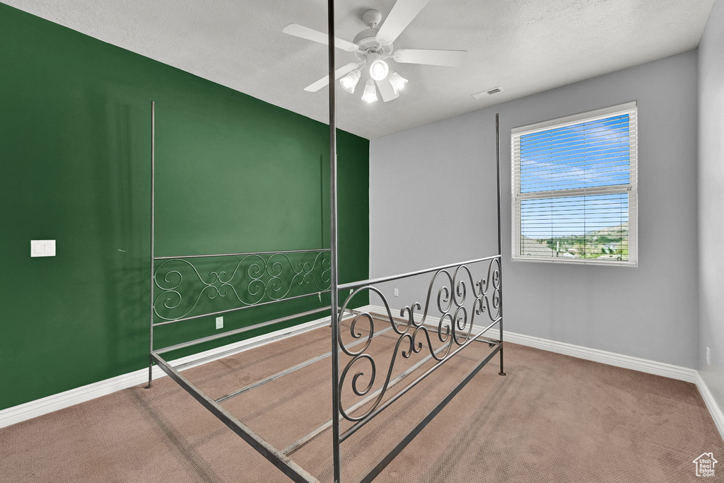 Carpeted bedroom featuring baseboards, visible vents, and a ceiling fan