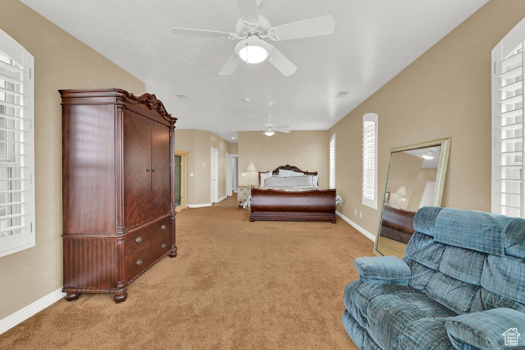 Bedroom with ceiling fan, light carpet, and baseboards