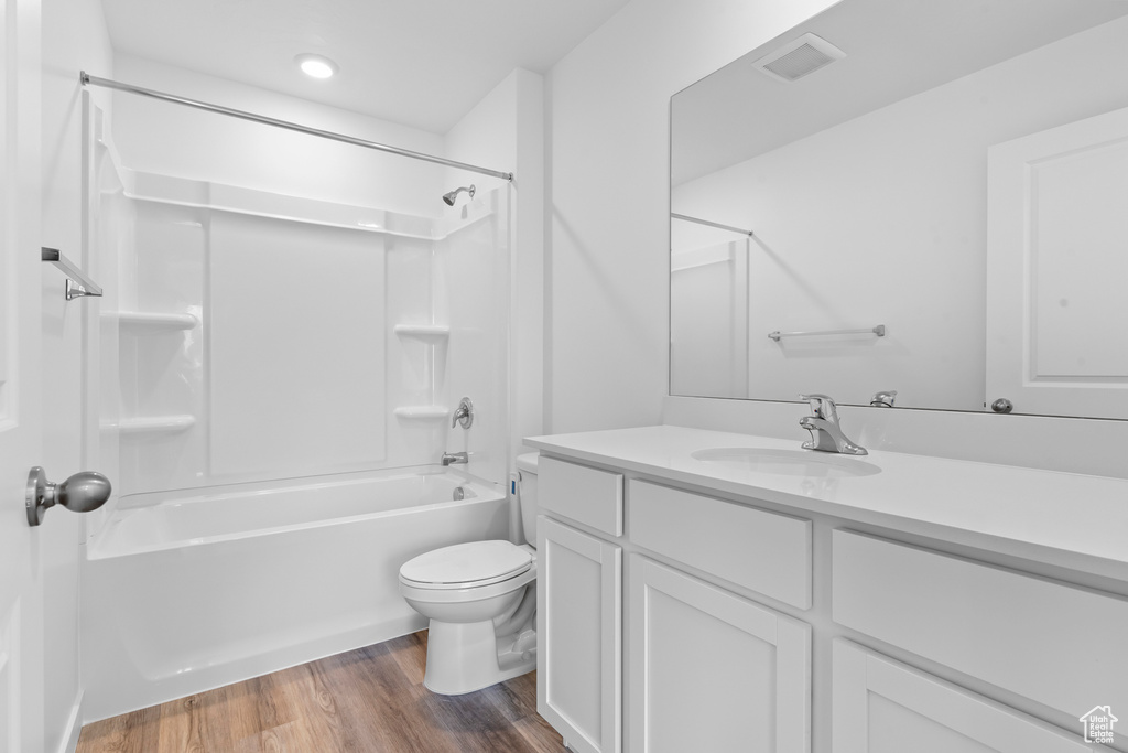 Bathroom with toilet, wood finished floors, vanity, and shower / tub combination