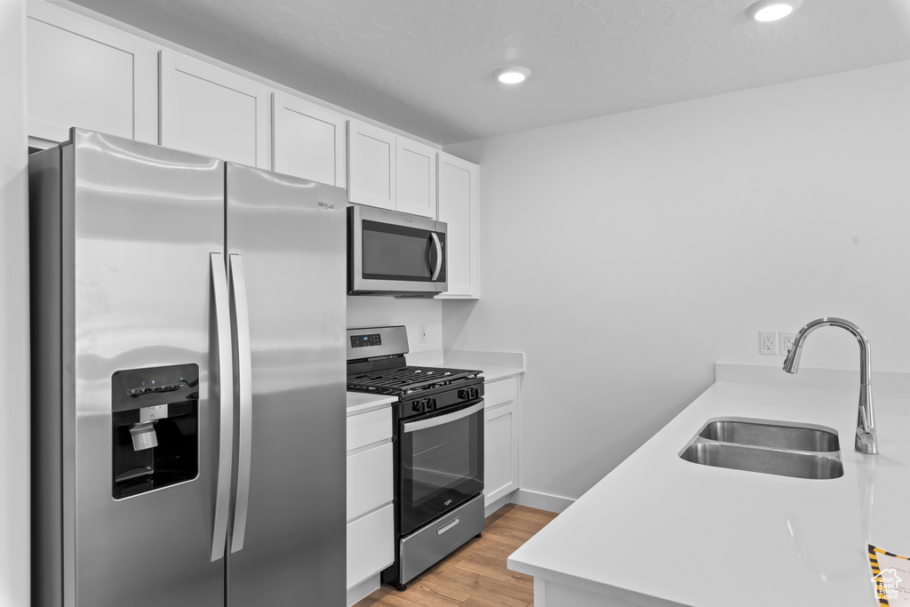 Kitchen featuring stainless steel appliances, a sink, white cabinets, light countertops, and recessed lighting
