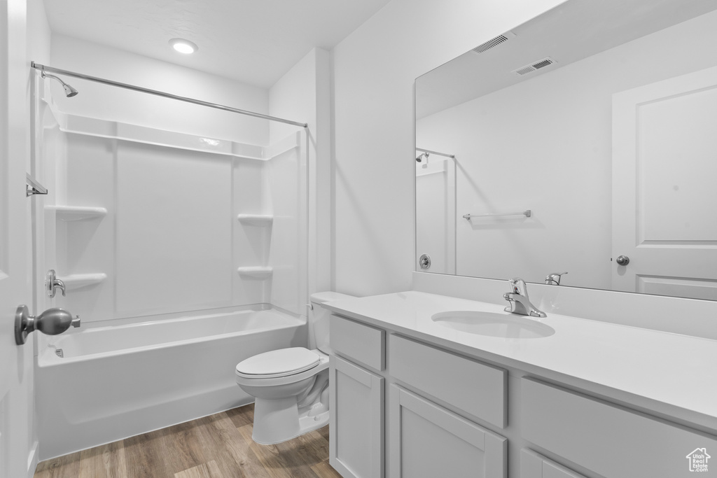 Full bathroom featuring wood finished floors, toilet, vanity, and  shower combination