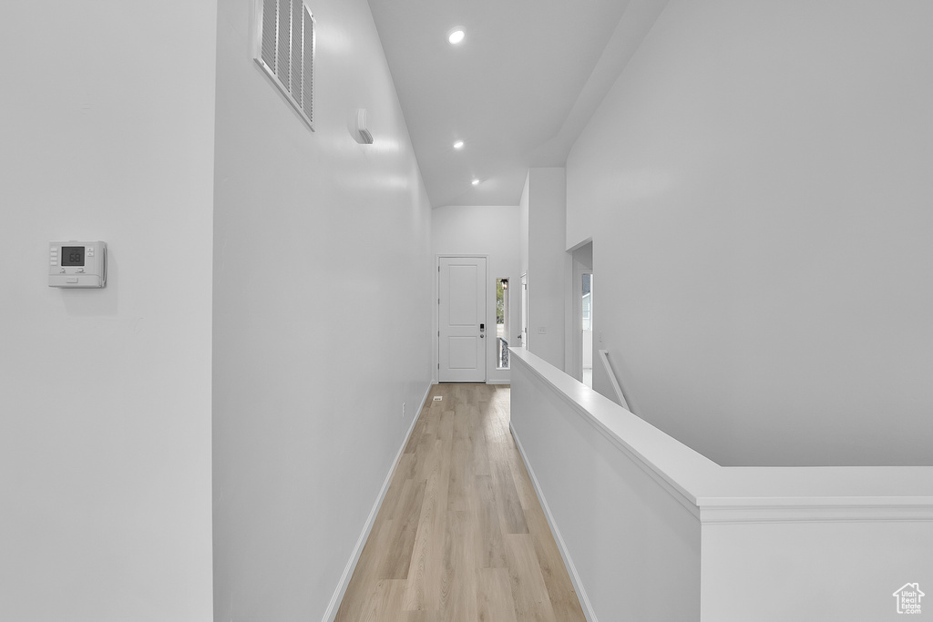 Hall with light wood-style floors, an upstairs landing, recessed lighting, baseboards, and a high ceiling