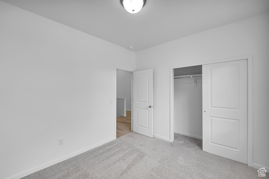 Unfurnished bedroom featuring carpet flooring, baseboards, and a closet