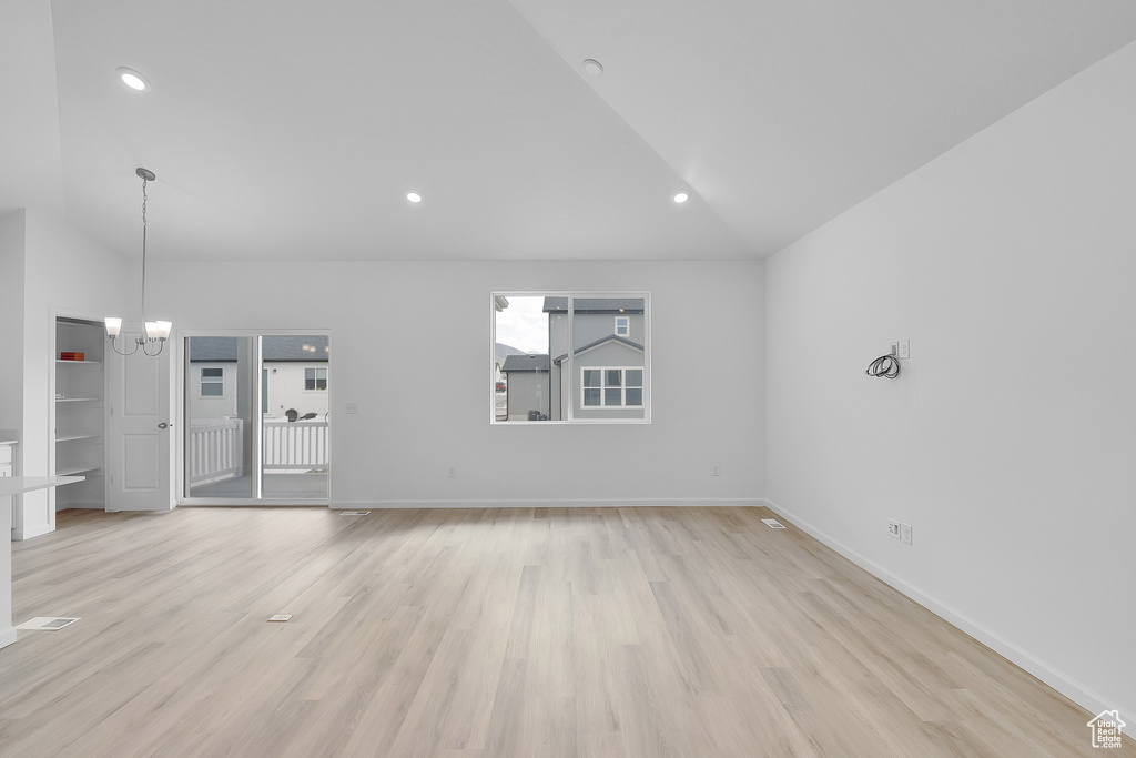 Unfurnished living room featuring vaulted ceiling, light wood-style floors, baseboards, recessed lighting, and a chandelier