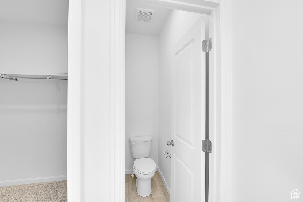 Bathroom with toilet, baseboards, and a spacious closet