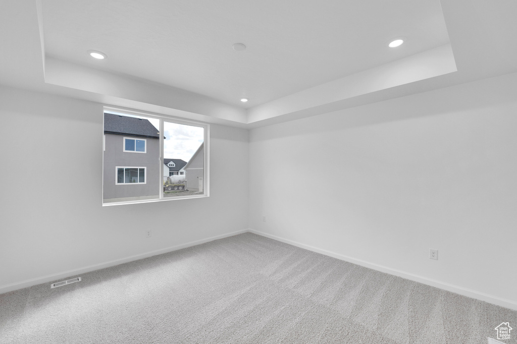 Unfurnished room featuring a raised ceiling, carpet flooring, baseboards, and recessed lighting