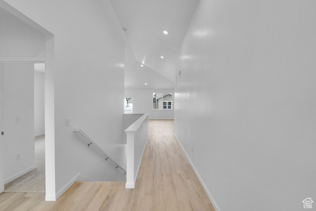Hall with an upstairs landing, light wood-type flooring, baseboards, recessed lighting, and vaulted ceiling