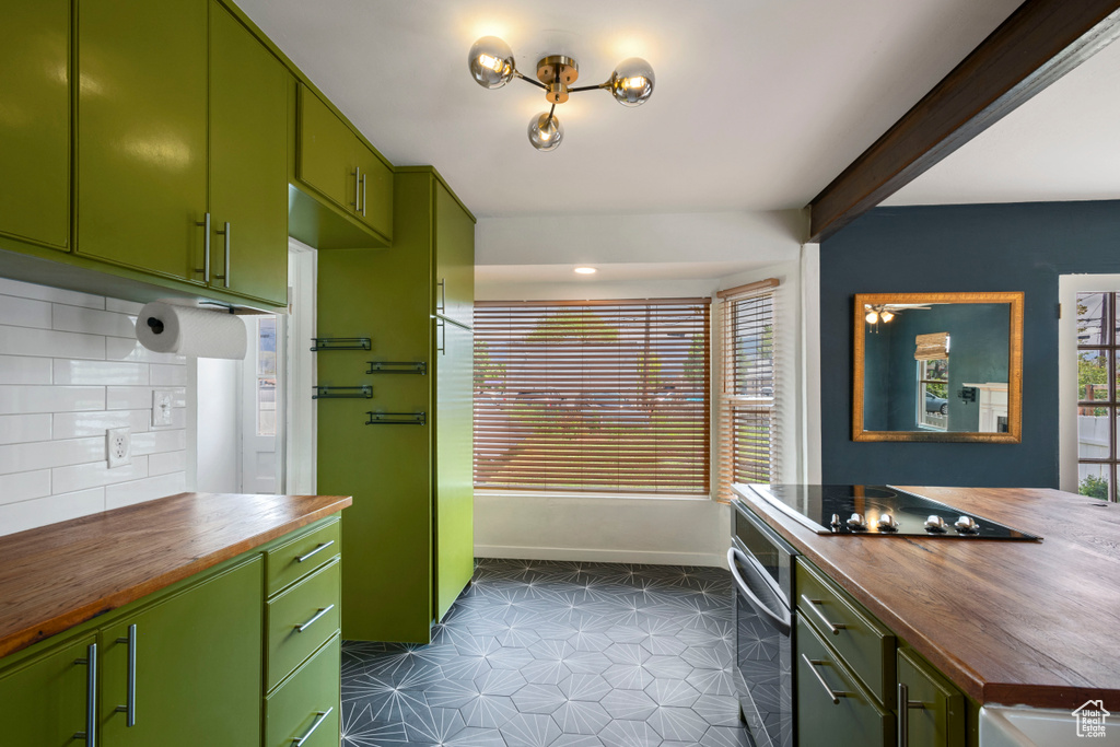 Kitchen featuring butcher block countertops, stainless steel oven, black electric stovetop, and green cabinetry