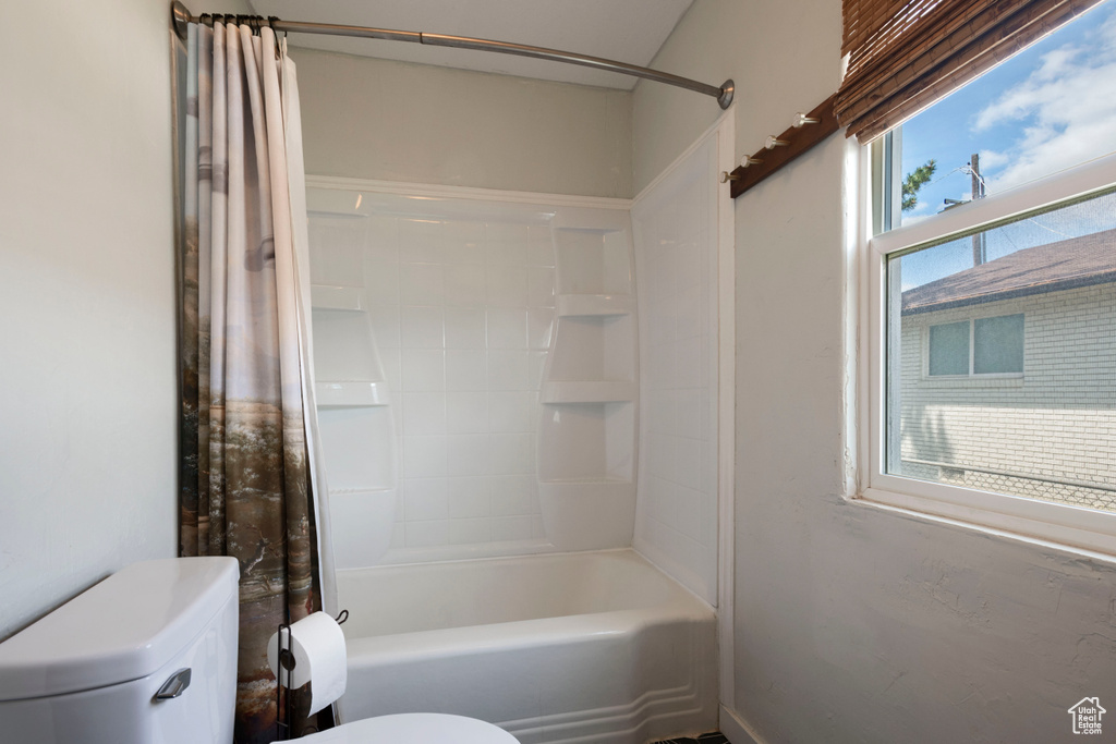 Bathroom featuring toilet and shower / bath combo with shower curtain