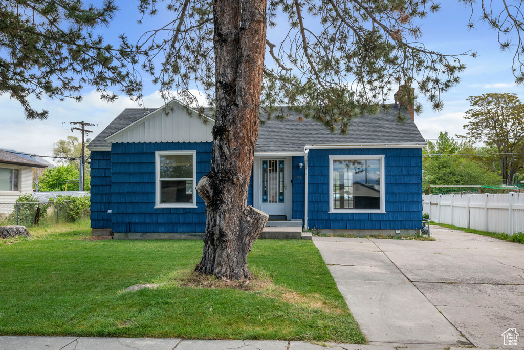 View of front of home with a chimney, a shingled roof, and concrete driveway