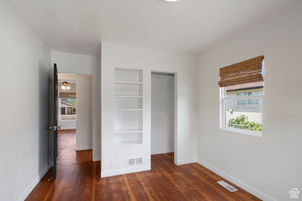 Unfurnished bedroom with baseboards, dark wood-style flooring, and a closet