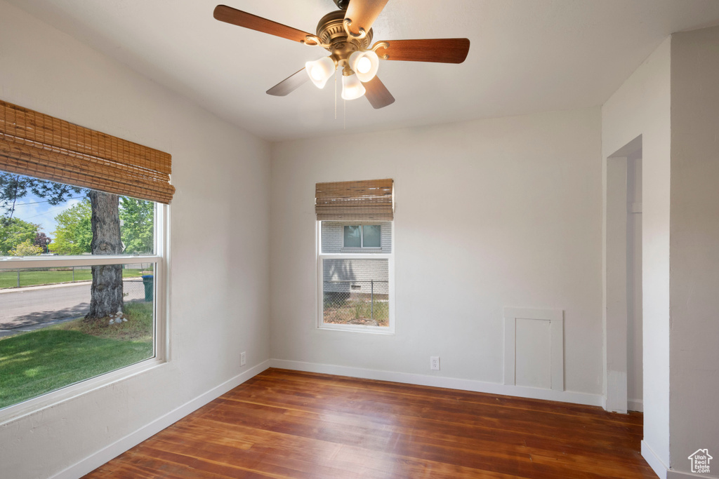 Empty room featuring wood finished floors, baseboards, and ceiling fan