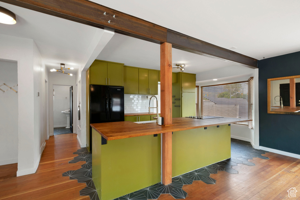 Kitchen featuring butcher block counters, a sink, green cabinetry, freestanding refrigerator, and dark wood-style floors