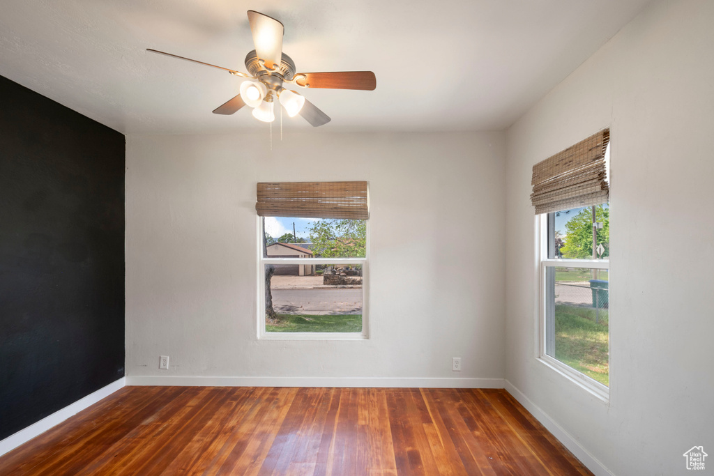 Empty room featuring hardwood / wood-style floors, baseboards, and a ceiling fan