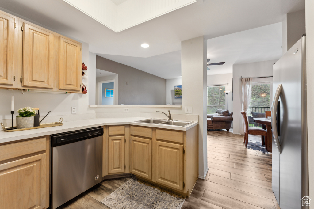 Kitchen featuring wood finished floors, light brown cabinetry, a sink, light countertops, and appliances with stainless steel finishes