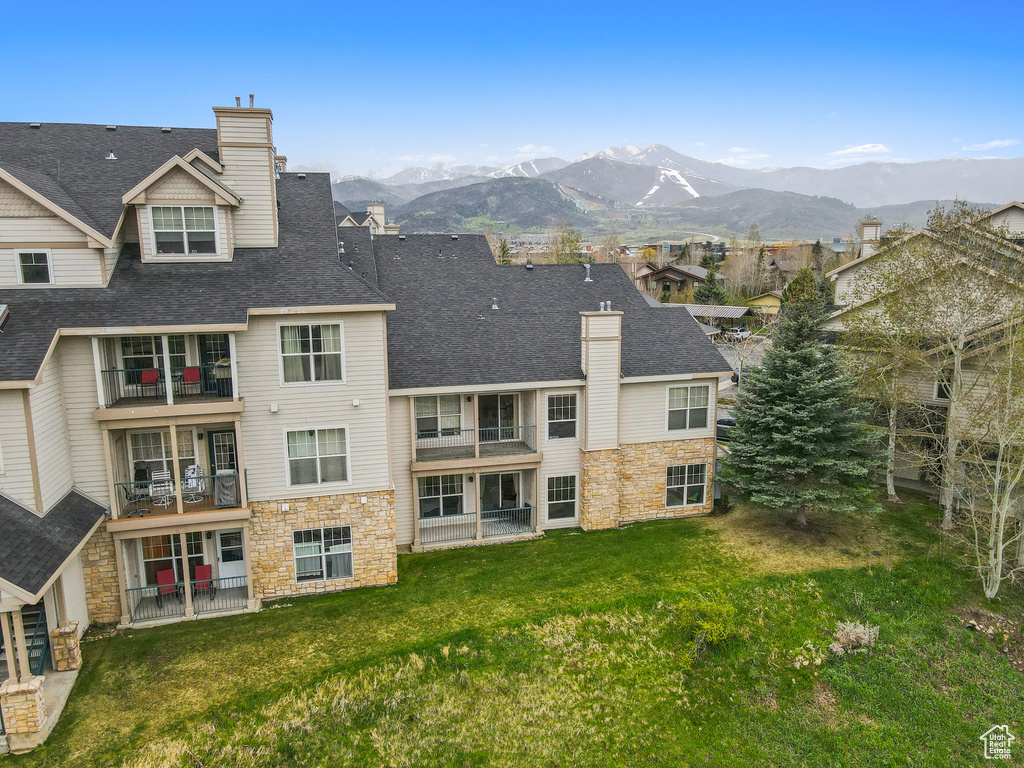 Exterior space with a chimney, a balcony, stone siding, and a mountain view