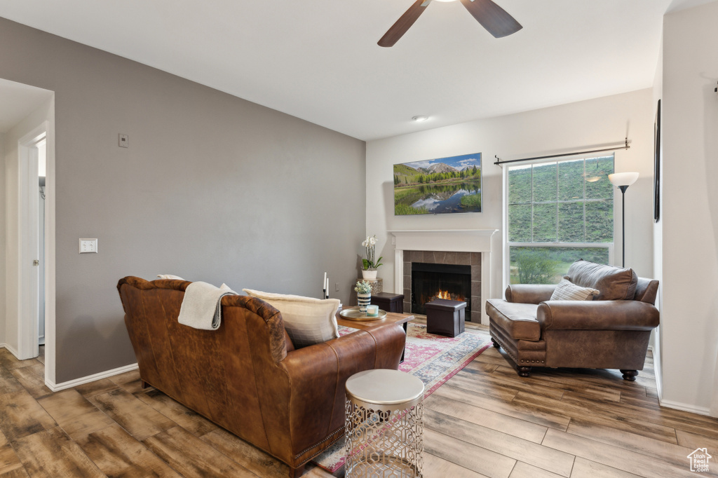 Living area with baseboards, a fireplace, ceiling fan, and wood finished floors