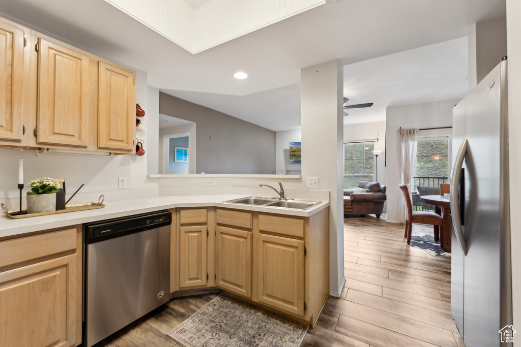 Kitchen featuring wood finished floors, a sink, stainless steel appliances, light brown cabinets, and light countertops
