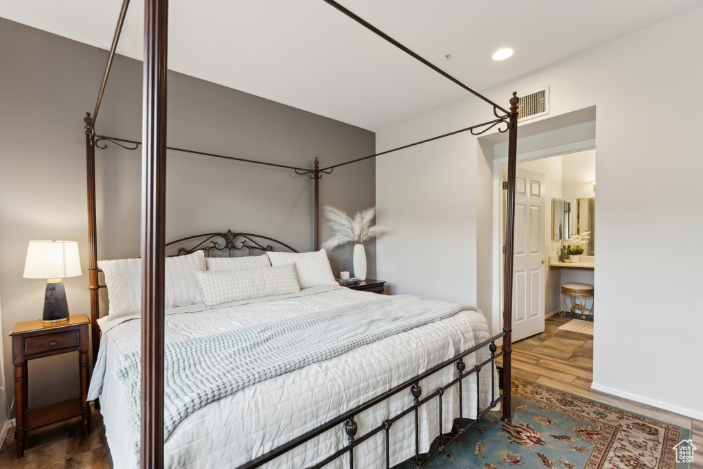Bedroom featuring recessed lighting, baseboards, ensuite bathroom, visible vents, and wood finished floors