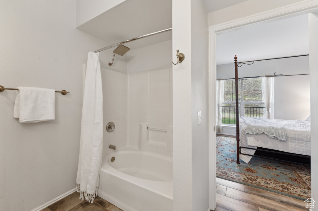 Ensuite bathroom with baseboards, ensuite bathroom, shower / bathtub combination with curtain, and wood finished floors