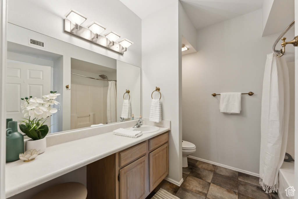 Full bathroom featuring toilet, baseboards, stone finish flooring, visible vents, and vanity