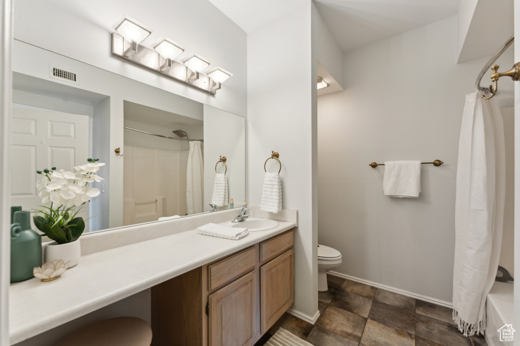 Bathroom featuring toilet, vanity, visible vents, stone finish flooring, and baseboards