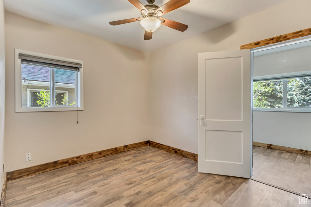 Empty room featuring wood finished floors, baseboards, and a ceiling fan