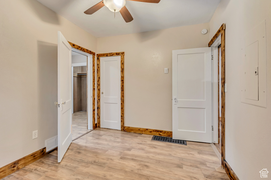 Unfurnished bedroom with electric panel, light wood-style floors, baseboards, a ceiling fan, and a closet