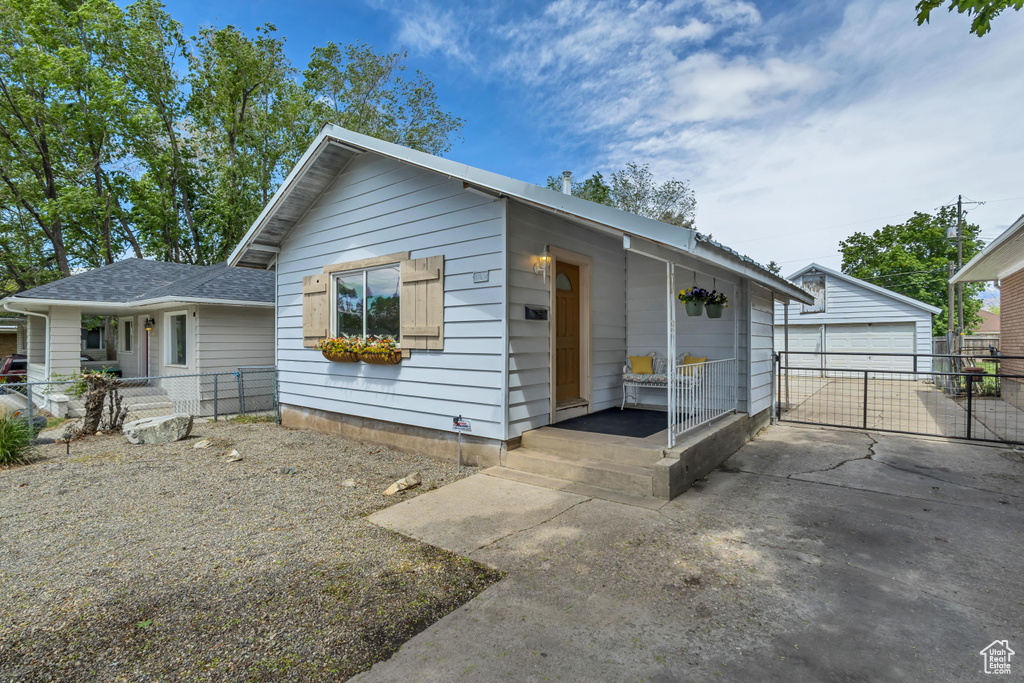 Ranch-style home featuring an outbuilding, fence, a garage, and a shingled roof
