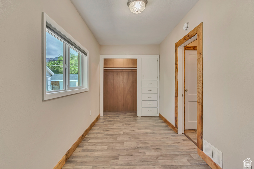 Hallway with light wood-style flooring and baseboards