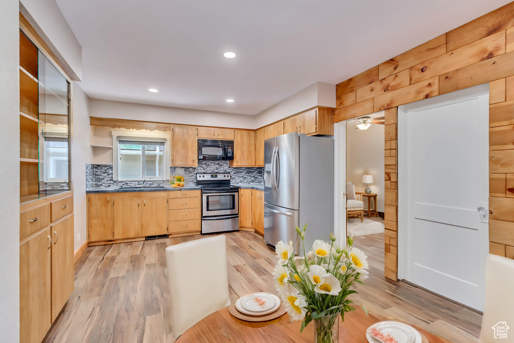 Kitchen with stainless steel appliances, a sink, tasteful backsplash, light brown cabinets, and light wood-type flooring