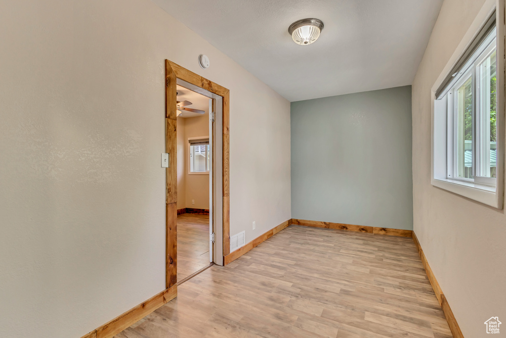 Unfurnished room featuring light wood-style floors, baseboards, and a smoke detector