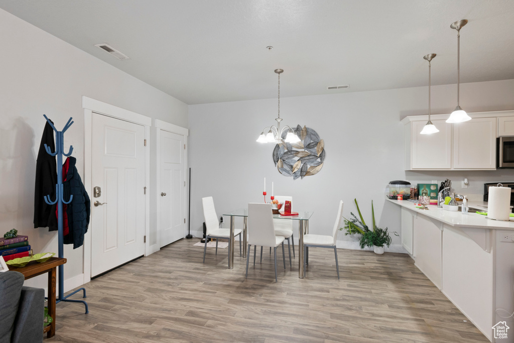 Kitchen featuring stainless steel microwave, light countertops, a chandelier, and light wood-style floors