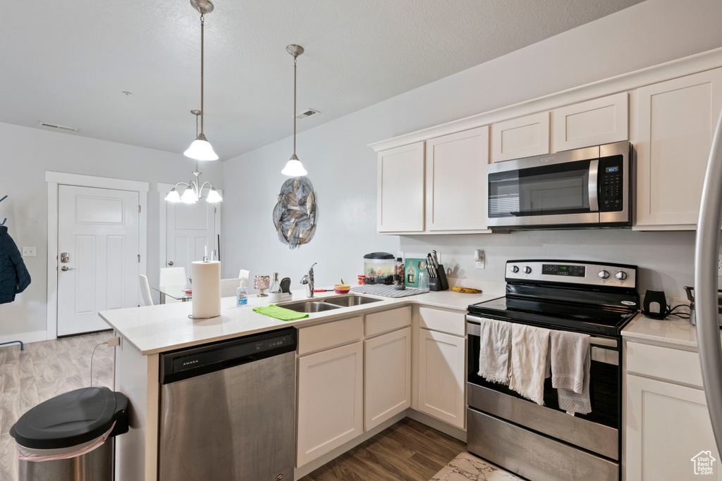 Kitchen featuring stainless steel appliances, a sink, a peninsula, and light countertops